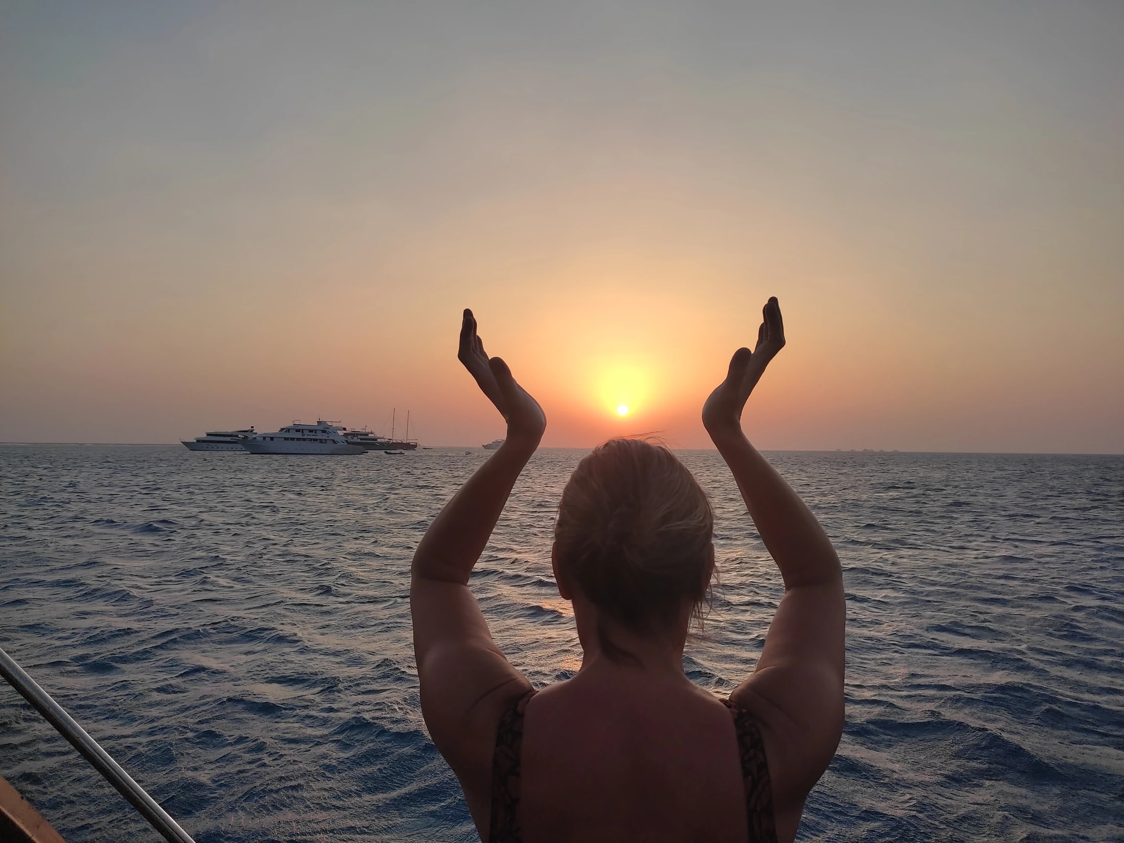 Isabelle face au soleil, les mains levées au-dessus de la mer.