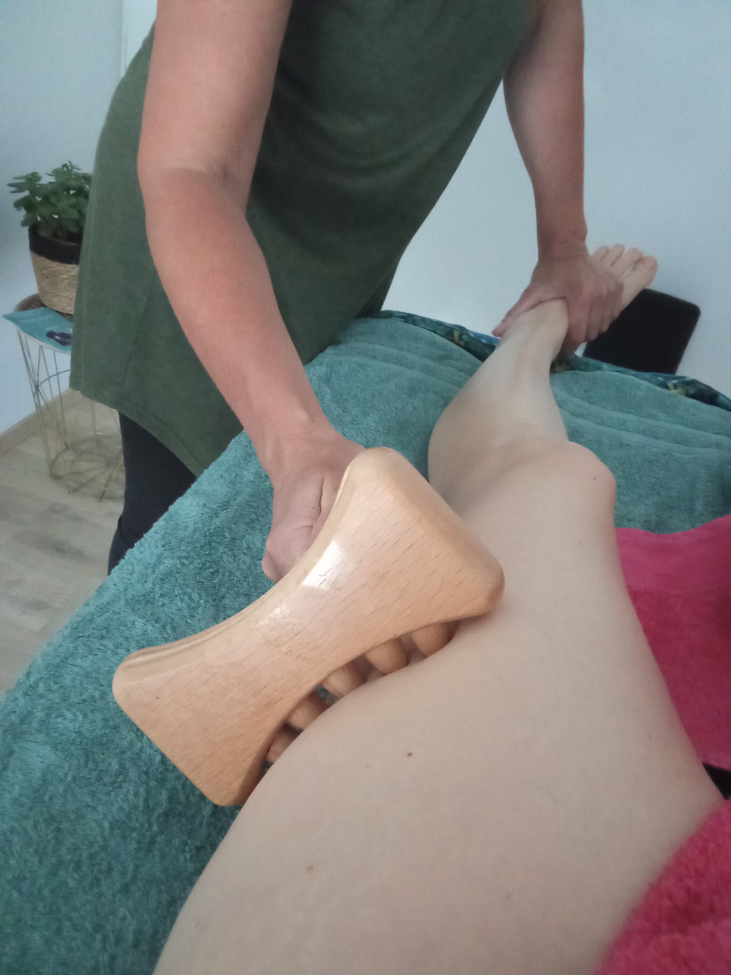 Séance de réflexo-madéro au cabinet ISAYIA, outil en bois sur la jambe